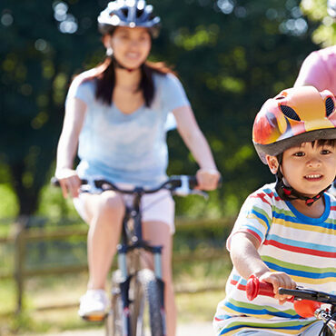 family riding bicycles wearing helmets